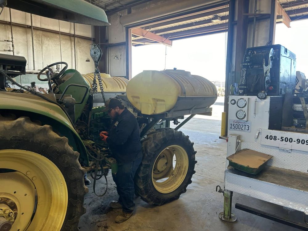 Technician servicing agricultural equipment in a shop bay