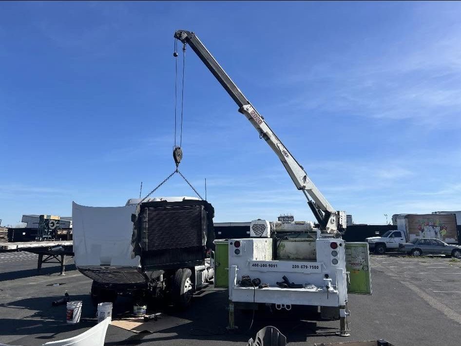 L&E Mechanics Services crane truck lifting a radiator out of a truck on location